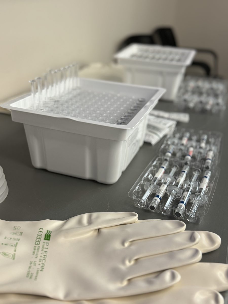 Production detail on the manufacturing line: trays, vials, and gloves on a work surface.
