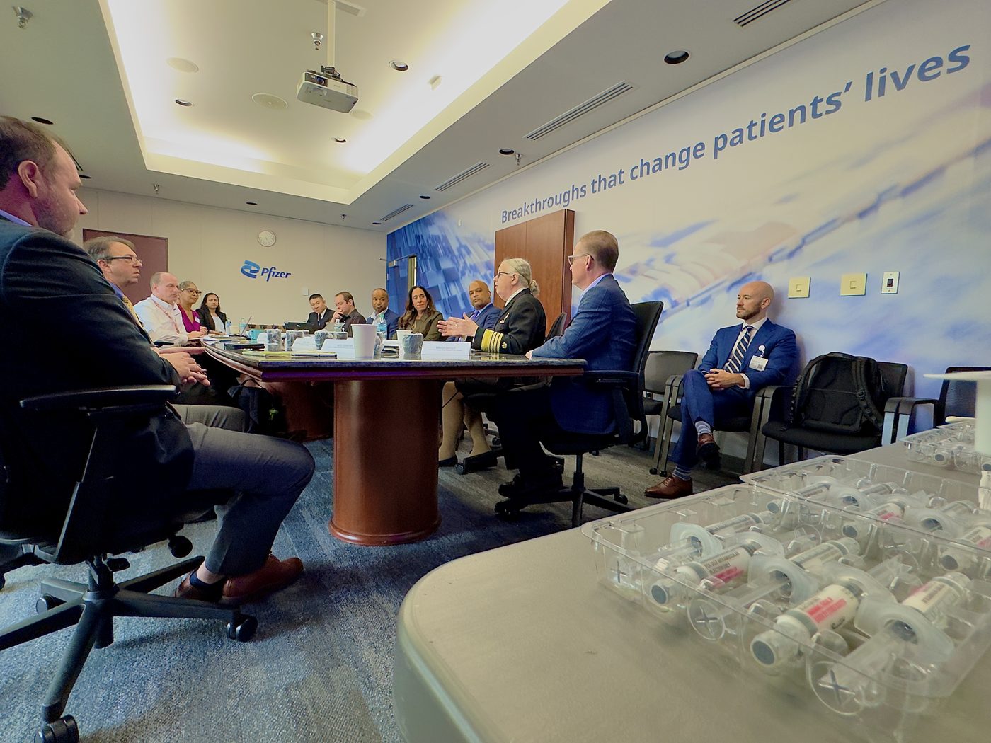 Leaders from Pfizer, HHS, the NIH, and the CDC seated around a boardroom table beneath the words Breakthroughs that change patients' lives.